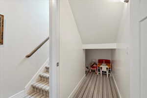 Stairs featuring vaulted ceiling, a textured ceiling, and carpet flooring