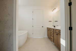 Bathroom with vanity, tile patterned flooring, and a tub