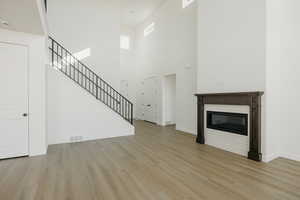 Unfurnished living room with light hardwood / wood-style floors and a high ceiling