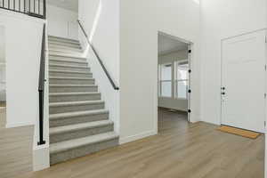 Entrance foyer with light hardwood / wood-style flooring and a high ceiling