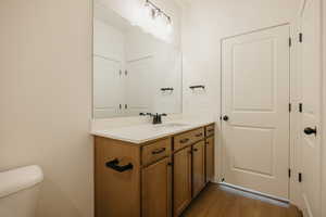 Bathroom with vanity, toilet, and wood-type flooring