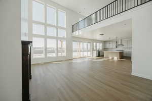 Unfurnished living room with a towering ceiling and light hardwood / wood-style flooring