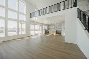 Unfurnished living room featuring a towering ceiling and light hardwood / wood-style floors