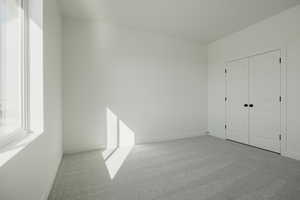 Unfurnished bedroom featuring light colored carpet and a closet