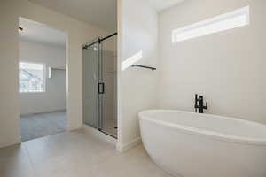 Bathroom with independent shower and bath, plenty of natural light, and tile patterned flooring