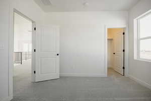 Unfurnished bedroom featuring light colored carpet and a walk in closet