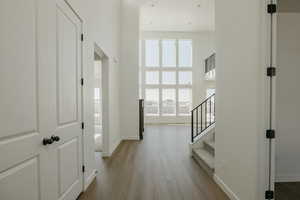 Corridor with a towering ceiling and light wood-type flooring