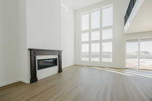 Unfurnished living room featuring light hardwood / wood-style flooring and a high ceiling