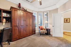 Sitting room featuring a tray ceiling, carpet floors, ornamental molding, and ceiling fan