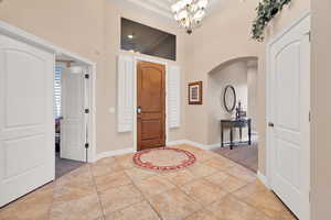 Foyer featuring light tile patterned floors, a chandelier, and a high ceiling