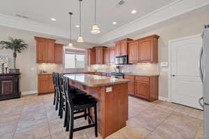 Kitchen with a breakfast bar area, decorative light fixtures, a center island, appliances with stainless steel finishes, and light stone countertops