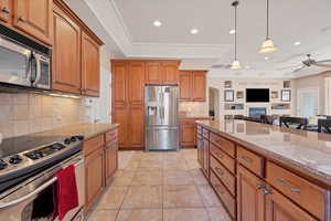 Kitchen featuring light tile patterned flooring, a breakfast bar, pendant lighting, light stone counters, and stainless steel appliances