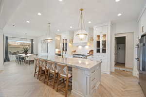 Kitchen featuring white cabinetry, light stone countertops, a large island, and light parquet flooring