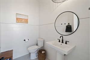 Bathroom with sink, toilet, tile patterned flooring, and tile walls