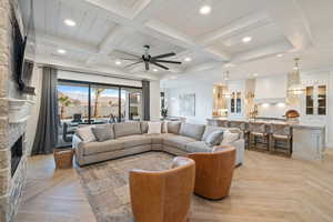 Living room featuring sink, beam ceiling, ceiling fan, a fireplace, and light parquet floors