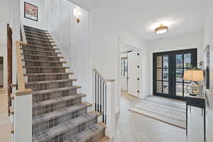 Foyer featuring french doors, a healthy amount of sunlight, and light parquet flooring