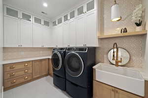 Laundry area with cabinets, washer and clothes dryer, and sink