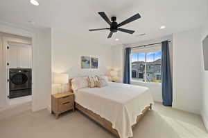 Bedroom with ceiling fan, independent washer and dryer, and light carpet