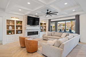 Living room featuring built in shelves, light parquet flooring, and beam ceiling