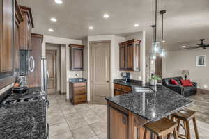 Kitchen featuring sink, hanging light fixtures, a kitchen breakfast bar, stainless steel appliances, and dark stone counters