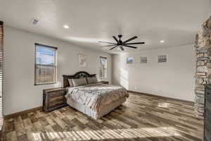 Bedroom with multiple windows, hardwood / wood-style flooring, and ceiling fan