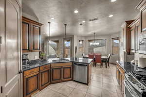 Kitchen featuring sink, decorative light fixtures, a textured ceiling, light tile patterned floors, and appliances with stainless steel finishes