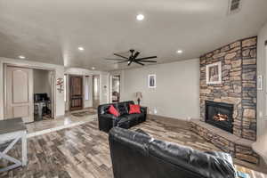 Living room featuring ceiling fan, light wood-type flooring, and a fireplace