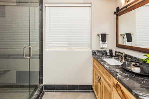 Bathroom featuring walk in shower, vanity, and tile patterned flooring