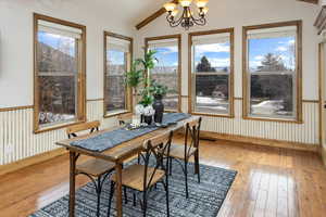 Dining space with wood-type flooring, lofted ceiling, and a chandelier