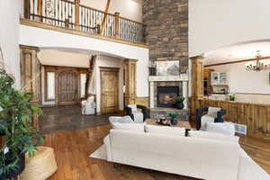 Living room with an inviting chandelier, dark hardwood / wood-style floors, a fireplace, ornamental molding, and ornate columns