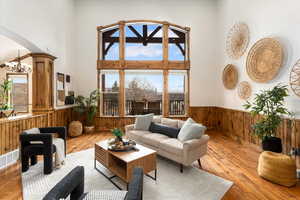 Living room with a towering ceiling, wooden walls, light hardwood / wood-style floors, and a chandelier