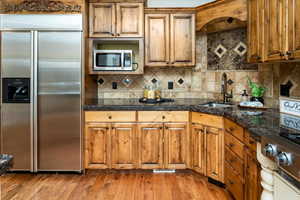 Kitchen featuring stainless steel appliances, sink, backsplash, and light wood-type flooring