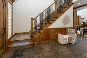 Staircase featuring a towering ceiling, wood walls, and ornate columns