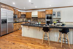 Kitchen featuring a kitchen bar, sink, a kitchen island with sink, stainless steel appliances, and light hardwood / wood-style floors