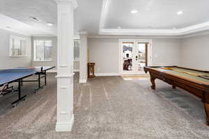 Game room featuring crown molding, carpet, a tray ceiling, french doors, and ornate columns