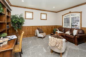 Living room featuring crown molding, carpet floors, and wooden walls