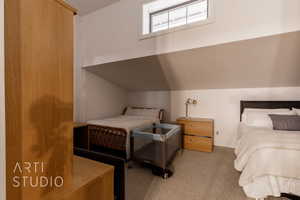 Bedroom with light colored carpet and vaulted ceiling