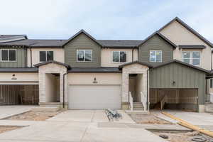 View of property featuring stone siding, stucco siding, concrete driveway, and an attached garage