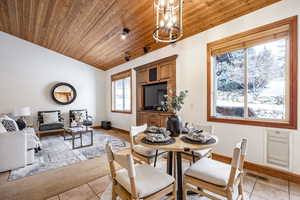 Dining area with light tile patterned flooring, lofted ceiling, an inviting chandelier, and wood ceiling