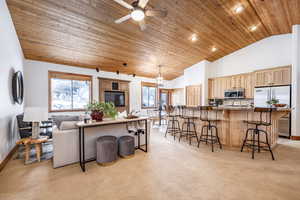 Living room featuring light carpet, high vaulted ceiling, wooden ceiling, and ceiling fan