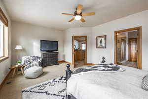 Bedroom featuring ceiling fan, connected bathroom, and light carpet