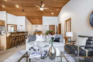 Carpeted living room featuring high vaulted ceiling, wooden ceiling, and ceiling fan