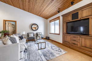 Carpeted living room featuring vaulted ceiling and wooden ceiling