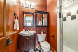 Bathroom with vanity, a shower with shower door, and toilet