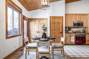 Dining space featuring wood ceiling, high vaulted ceiling, a chandelier, and light tile patterned flooring