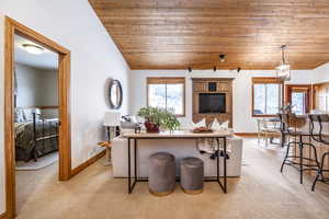 Carpeted living room featuring lofted ceiling, a notable chandelier, and wooden ceiling