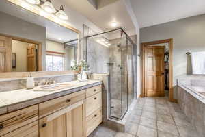 Bathroom featuring shower with separate bathtub, vanity, and tile patterned floors