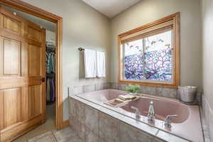 Bathroom featuring tiled tub and tile patterned floors