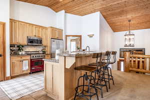 Kitchen with light brown cabinetry, high vaulted ceiling, wooden ceiling, stainless steel appliances, and decorative backsplash