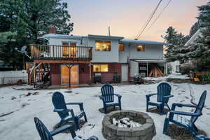 Snow covered back of property with a wooden deck, an outdoor fire pit, and central air condition unit